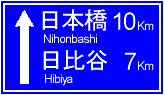 長方形で青い背景で「日本橋10キロメートル先、日比谷7キロメートル先」と書かれた標識