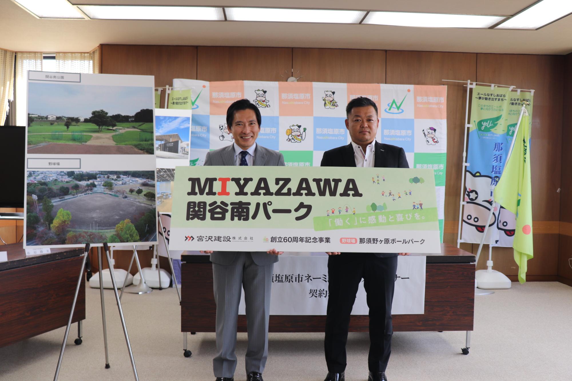 二人の男性が「MIYAZAWA関谷南パーク、那須野ヶ原ボールパーク」と書かれたプレートを持って、並んで立っている写真