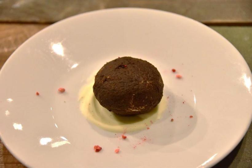 白いお皿に敷かれたホワイトチョコの上に茶色く丸い形のデザートの写真
