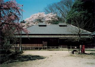 左側と後ろに花の咲いた木があり、乃木希典那須野旧宅(のぎまれすけなすのきゅうたく)が建っている写真