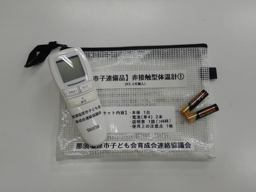 白い非接触型体温計と電池とジッパー付きの袋の写真