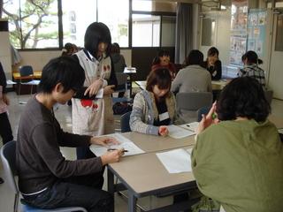 室内で机を囲み、筆記用具を手に学習している参加者たちの写真