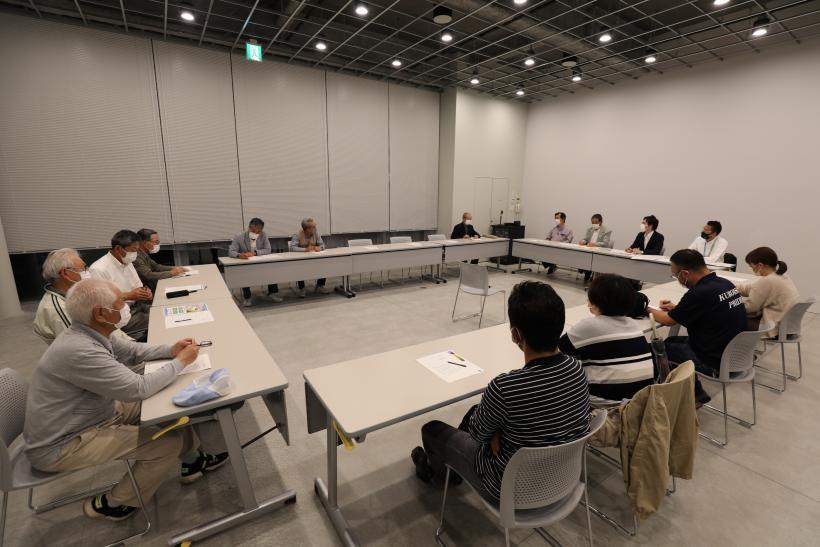 会議室の机がロの字型に並べられ、参加者が着席している写真