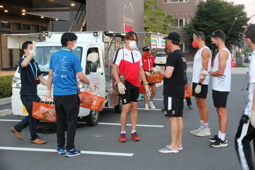ホテルの玄関前にやって来た移動販売車で買い物をするオーストリアの選手たちの写真