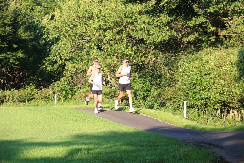 オーストリア選手たちによるランのトレーニング風景の写真。塩原カントリークラブ敷地内の舗装道を集団で走る様子が確認できる