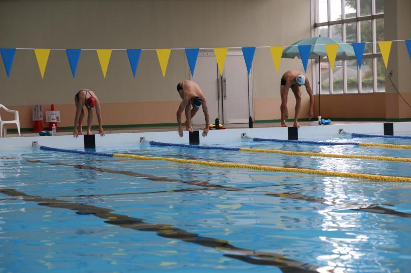 スイムのトレーニングにて、オーストリア選手たちが飛び込み台から一斉にプールへ飛び込もうとしている瞬間を捉えた写真