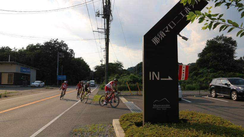 バイクのトレーニングを終えて、オーストリア選手たちがロードバイクに乗ったまま車道から那須マロニエホテルの駐車場に入ろうとしている瞬間を捉えた写真