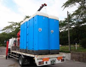 トラックに載せられて移動している仮設トイレの写真